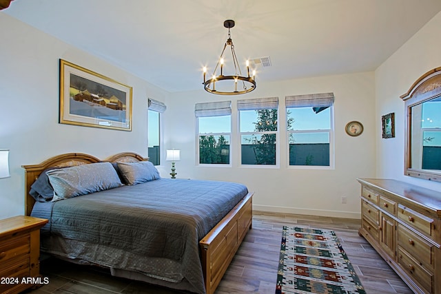 bedroom with dark hardwood / wood-style floors and an inviting chandelier