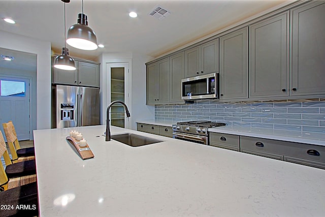 kitchen with sink, stainless steel appliances, tasteful backsplash, decorative light fixtures, and gray cabinets