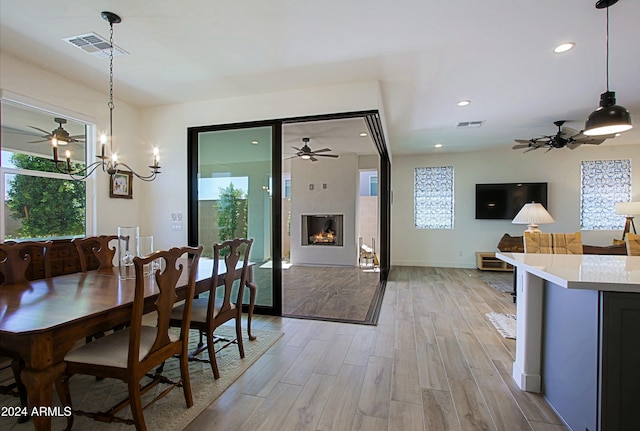 dining area featuring a fireplace, light hardwood / wood-style floors, and a notable chandelier