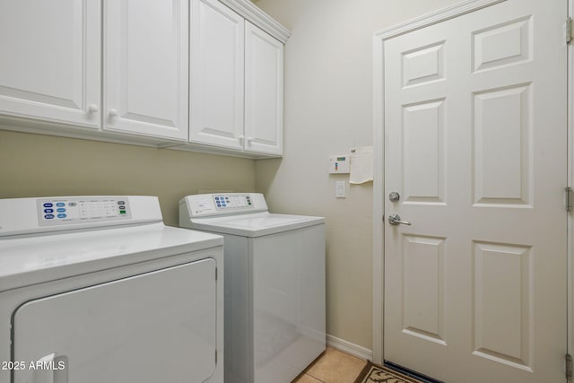 clothes washing area featuring cabinets, washer and clothes dryer, and light tile patterned floors