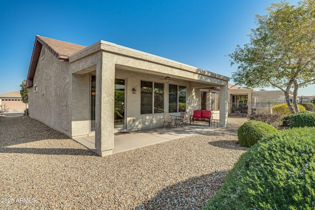 rear view of property featuring ceiling fan and a patio area