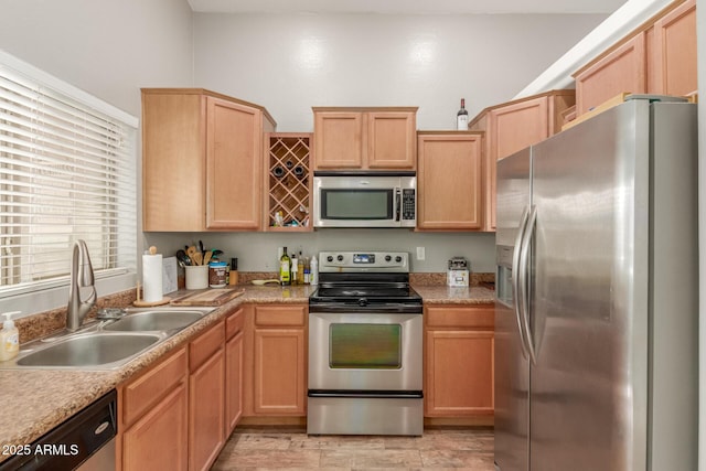 kitchen featuring appliances with stainless steel finishes, light brown cabinetry, and sink