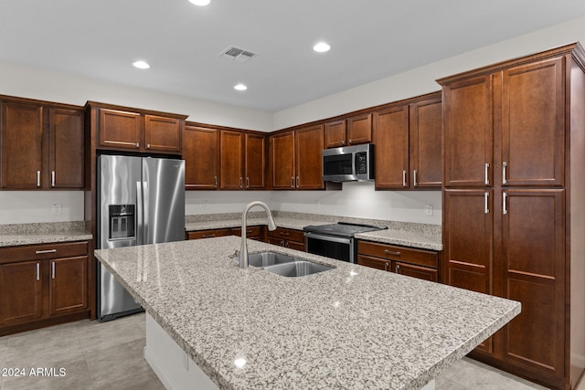 kitchen with light stone countertops, a kitchen island with sink, sink, and stainless steel appliances