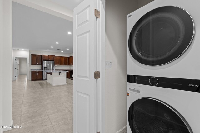 clothes washing area featuring stacked washer / dryer and light tile patterned flooring