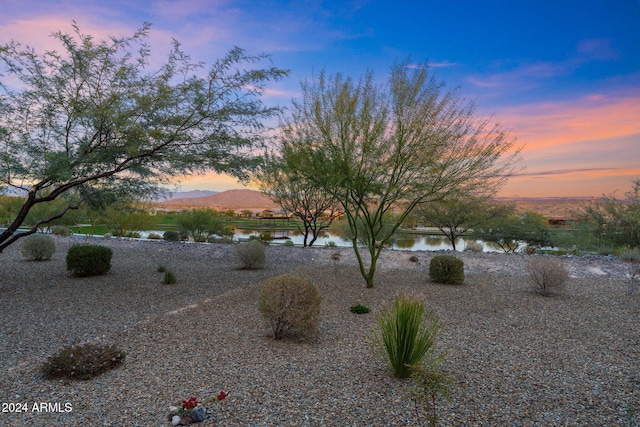 yard at dusk featuring a water and mountain view