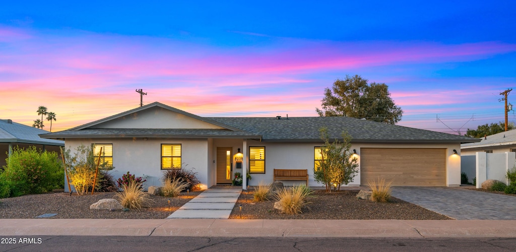 ranch-style house featuring stucco siding, a garage, and decorative driveway