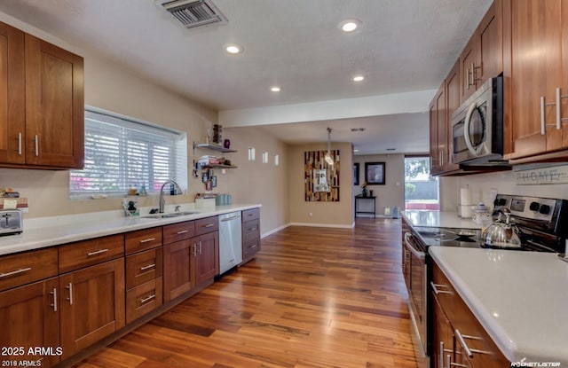 kitchen with pendant lighting, appliances with stainless steel finishes, sink, and hardwood / wood-style floors