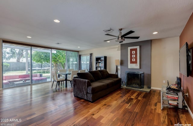 living room featuring ceiling fan, hardwood / wood-style floors, and a wall of windows