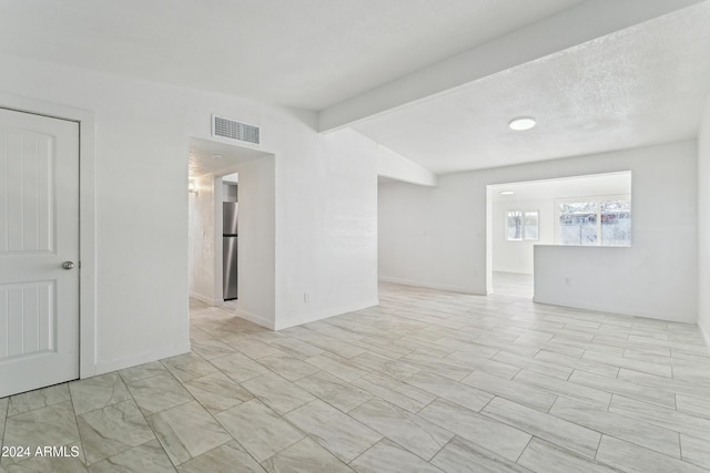 unfurnished room with lofted ceiling with beams