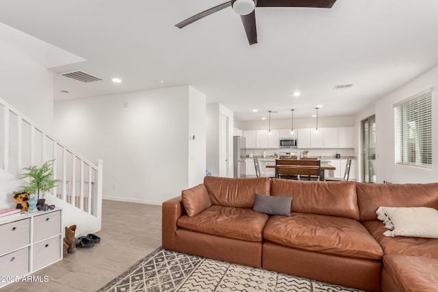 living room with ceiling fan and light hardwood / wood-style flooring