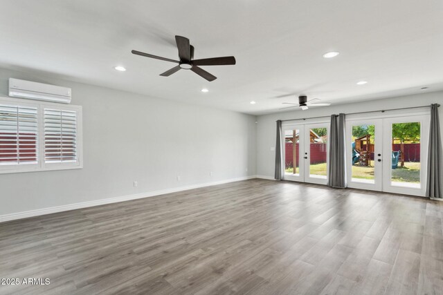 unfurnished room featuring a wall mounted AC, french doors, recessed lighting, wood finished floors, and ceiling fan