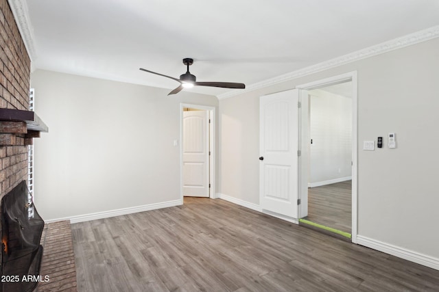 unfurnished living room featuring a fireplace, wood finished floors, ceiling fan, baseboards, and ornamental molding
