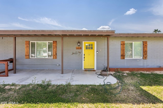 ranch-style home featuring brick siding, covered porch, and a front yard