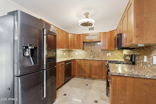 kitchen featuring stainless steel appliances, brown cabinetry, granite floors, and a sink