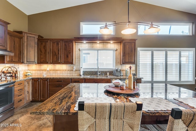 kitchen featuring a kitchen island, pendant lighting, sink, light stone counters, and electric stove