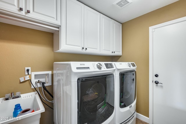 clothes washing area with independent washer and dryer, sink, and cabinets