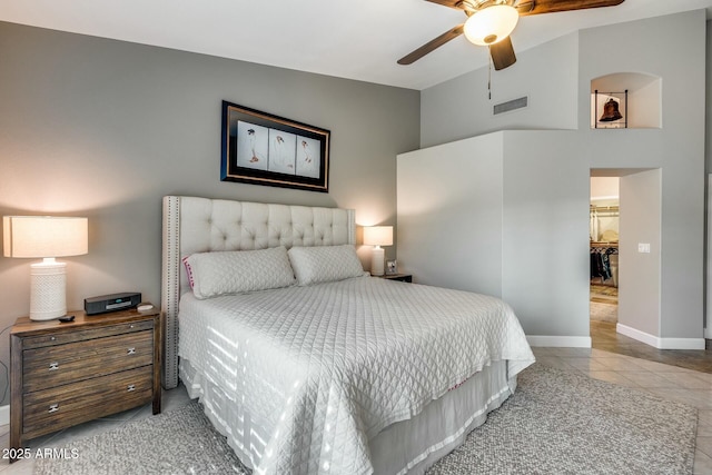 bedroom with light tile patterned floors, a walk in closet, and ceiling fan