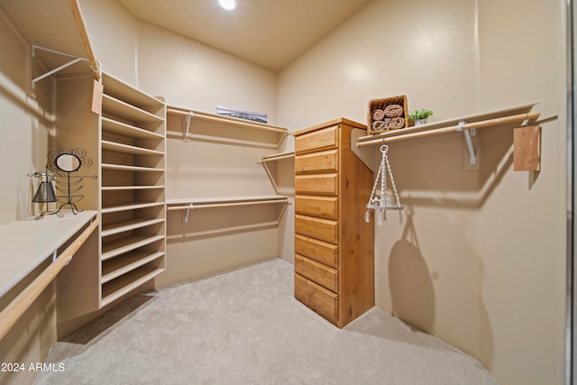 spacious closet with lofted ceiling and light colored carpet