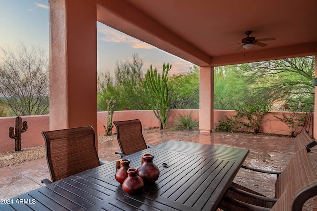 patio terrace at dusk featuring ceiling fan and a deck