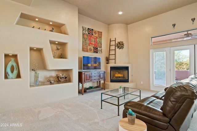 carpeted living room with a large fireplace and ceiling fan