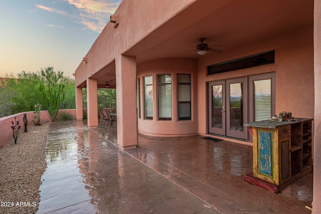 patio terrace at dusk featuring french doors and ceiling fan