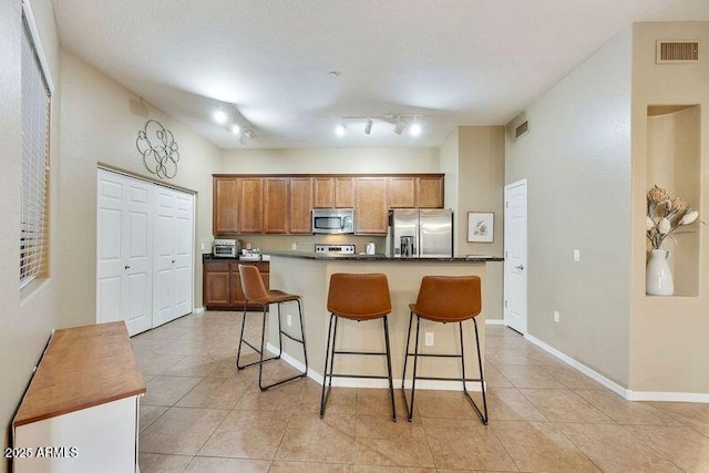 3330 S Gilbert Rd Unit 2090, Chandler, AZ 85286 - kitchen featuring light tile patterned floors, baseboards, a kitchen island, a breakfast bar, and stainless steel appliances