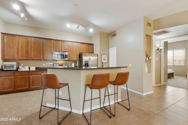 3330 S Gilbert Rd Unit 2090, Chandler, AZ 85286 - kitchen with brown cabinetry, a kitchen island, appliances with stainless steel finishes, and a breakfast bar