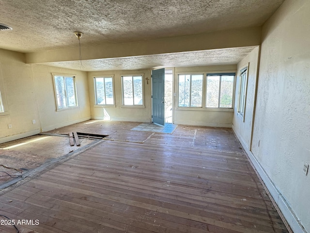 spare room with visible vents, a textured wall, a textured ceiling, and hardwood / wood-style flooring