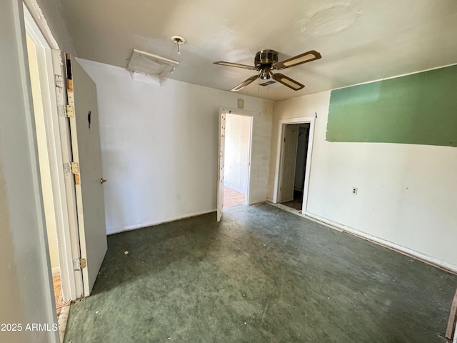 spare room featuring attic access, unfinished concrete floors, and a ceiling fan