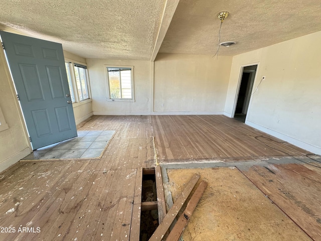 empty room featuring hardwood / wood-style flooring, baseboards, and a textured ceiling