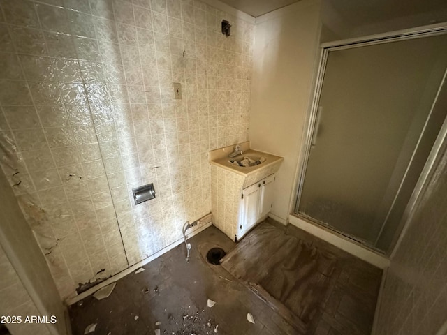 full bath featuring a sink, a stall shower, and tile walls