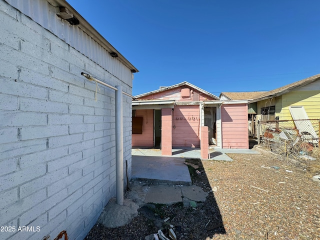 view of property exterior with fence and a patio