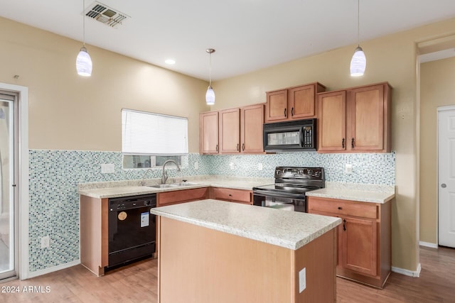 kitchen featuring a center island, sink, light hardwood / wood-style floors, pendant lighting, and black appliances