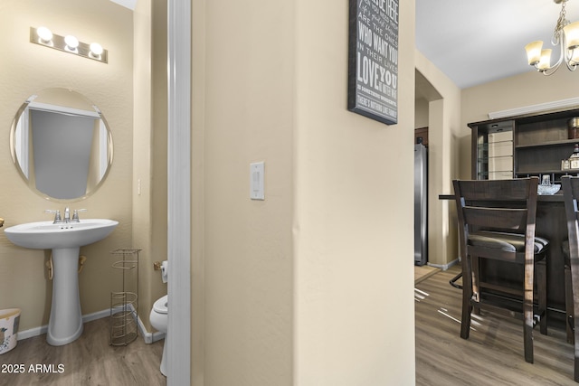2111 N 77th Gln, Phoenix, AZ 85035 - bathroom featuring wood finished floors, toilet, a chandelier, and baseboards