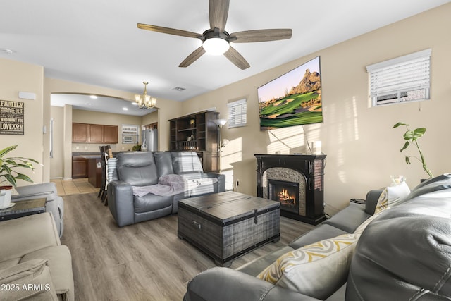 2111 N 77th Gln, Phoenix, AZ 85035 - living area with a ceiling fan, light wood-type flooring, a chandelier, and a lit fireplace