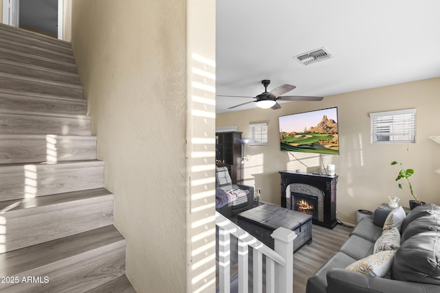 2111 N 77th Gln, Phoenix, AZ 85035 - living room featuring wood finished floors, stairs, ceiling fan, and a lit fireplace