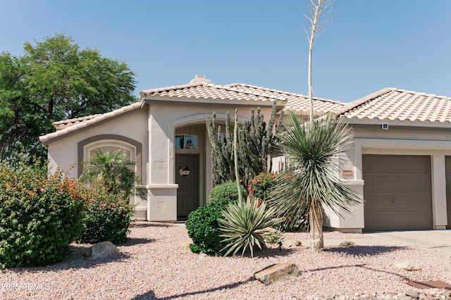 mediterranean / spanish-style house with an attached garage, a tile roof, and stucco siding