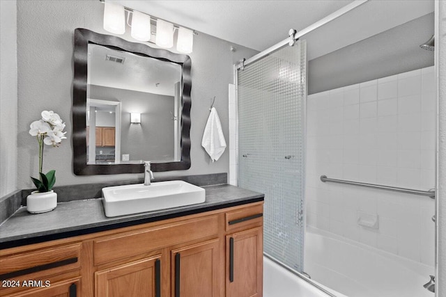 bathroom featuring combined bath / shower with glass door, vanity, and visible vents