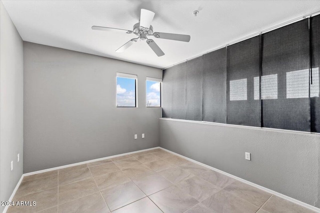 empty room featuring a ceiling fan, baseboards, and tile patterned floors