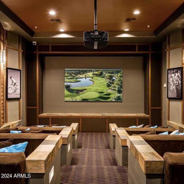 home theater room with a tray ceiling, visible vents, dark colored carpet, and recessed lighting