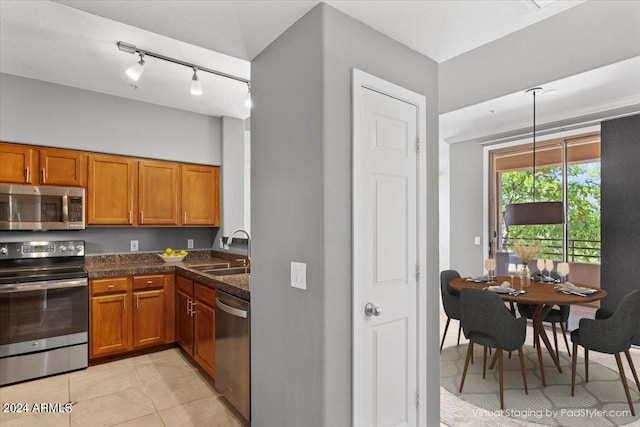 kitchen featuring stainless steel appliances, brown cabinetry, a sink, and light tile patterned floors