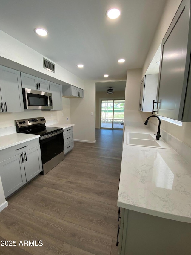 kitchen with sink, dark hardwood / wood-style flooring, gray cabinets, and appliances with stainless steel finishes