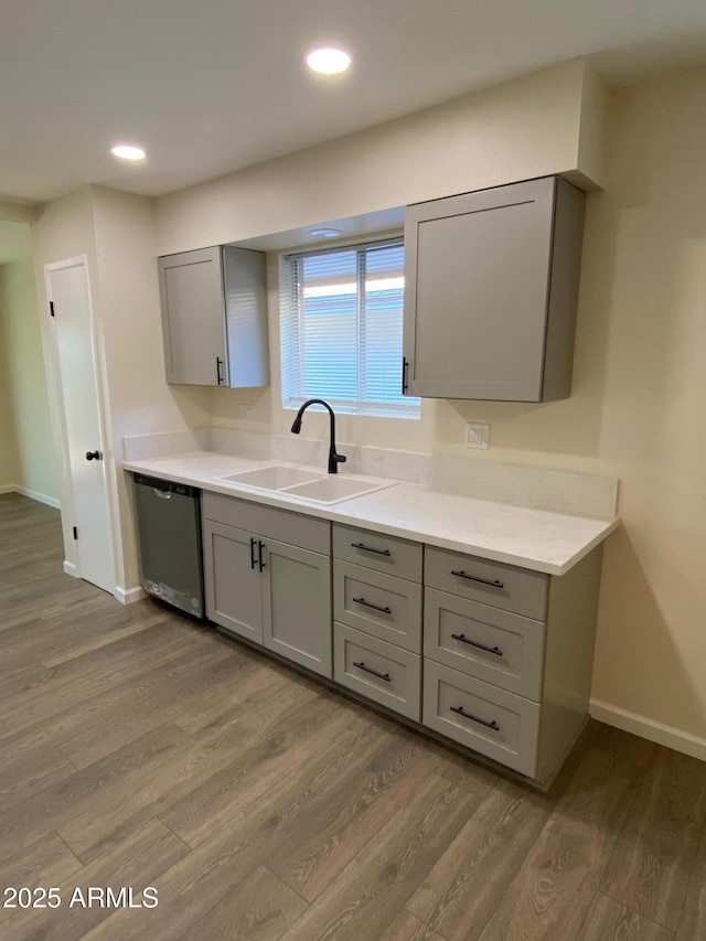 kitchen featuring stainless steel dishwasher, light hardwood / wood-style flooring, gray cabinetry, and sink