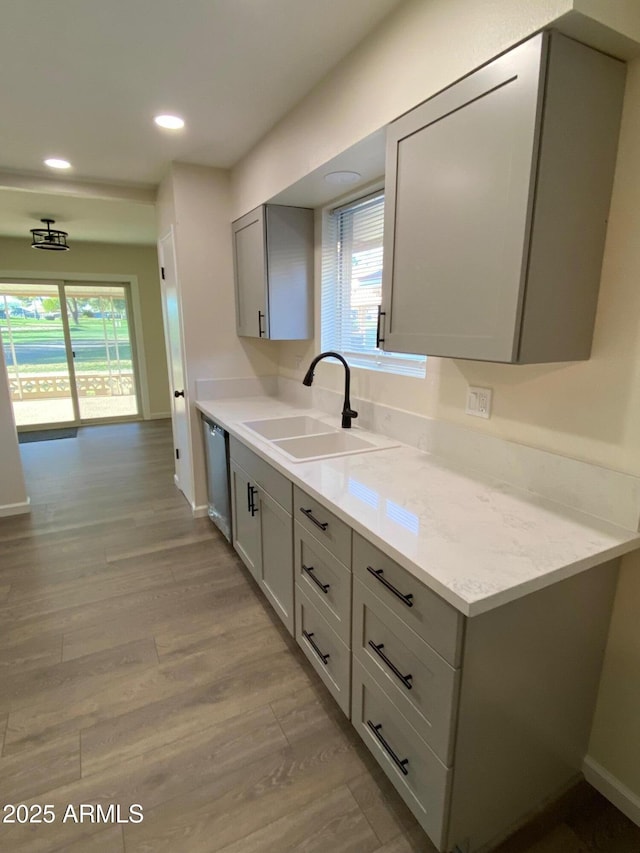 kitchen featuring stainless steel dishwasher, sink, light wood-type flooring, and gray cabinets