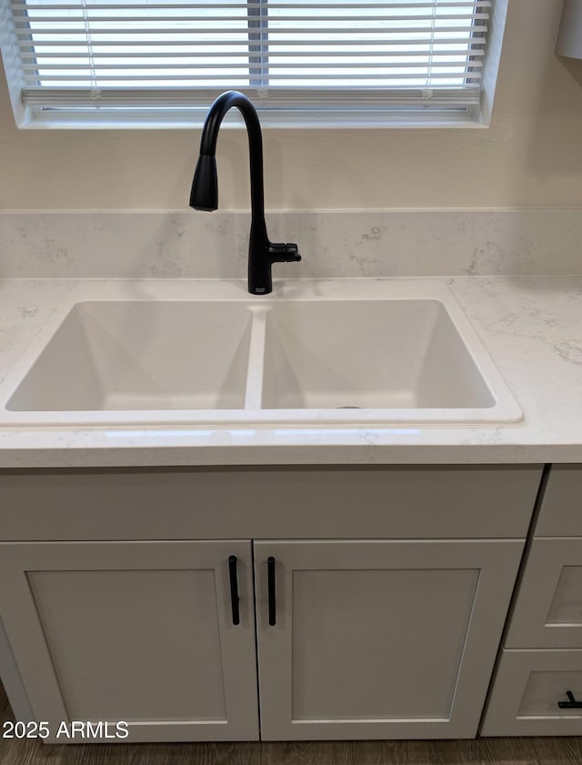 room details featuring light stone counters, gray cabinetry, and sink