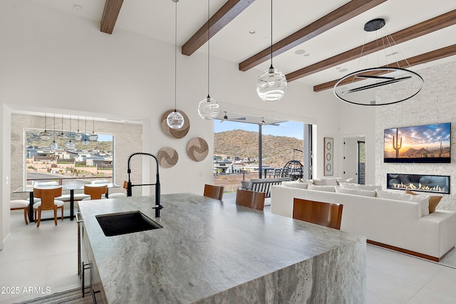 14108 E Harmony Ln, Fountain Hills, AZ 85268 - kitchen with light tile patterned floors, a large fireplace, a sink, a towering ceiling, and pendant lighting