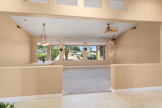 unfurnished living room featuring light carpet, ceiling fan with notable chandelier, and lofted ceiling