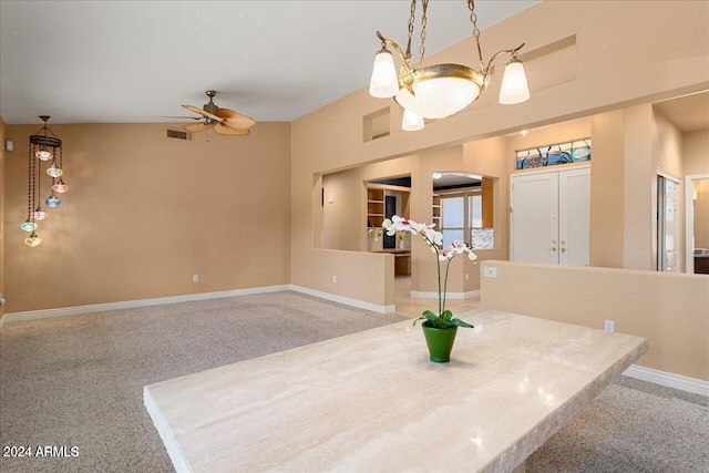 carpeted dining room with ceiling fan with notable chandelier