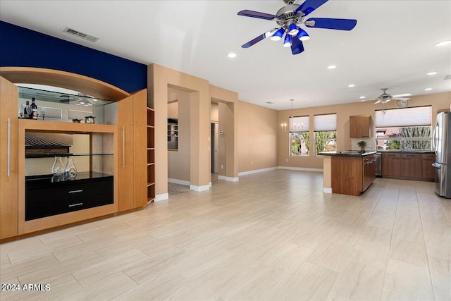 kitchen featuring sink, stainless steel fridge, hanging light fixtures, a kitchen island, and ceiling fan with notable chandelier