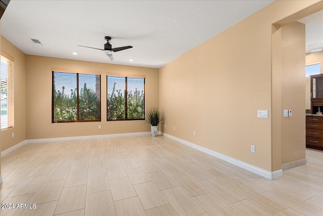 empty room with light hardwood / wood-style flooring, a wealth of natural light, and ceiling fan